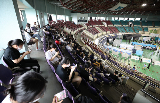 '백신접종 명단에 없어' 관중석에 대기하는 고3·교직원  고등학교 3학년 학생들과 교직원 등을 대상으로 한 백신 1차 접종이 시작된 19일 경기 부천체육관에 마련된 예방접종센터에서 경기예고 학생들과 교직원이 관중석에서 대기하고 있다. 연합